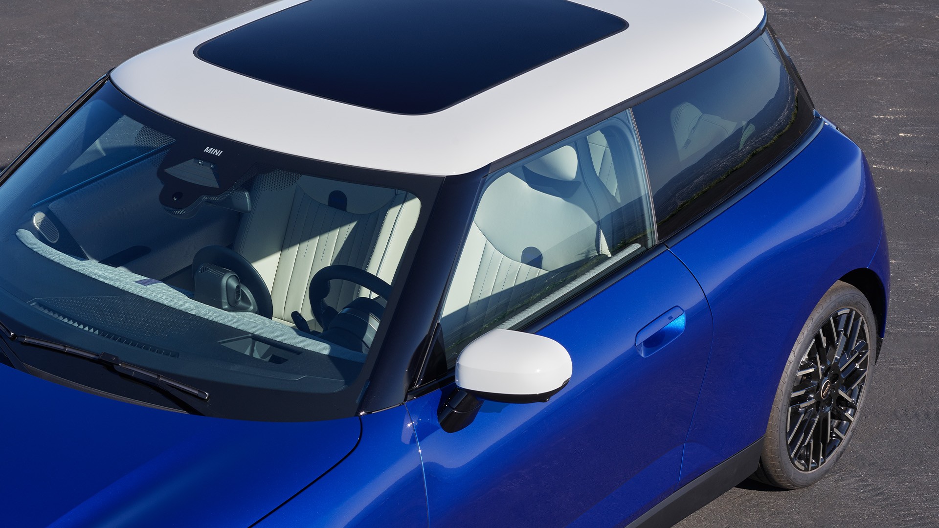 Blár MINI Cooper séður ofan frá með hvítu þaki og víðáttumiklu glerþaki